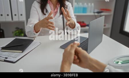 Doctor and patient in a hospital room having a discussion while a woman gestures during a consultation indoors, with focus on hands and medical equipm Stock Photo