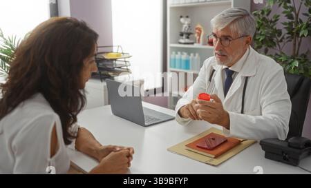 Doctor talking to patient in modern clinic office, discussing healthcare options with woman in a professional medical setting, featuring diverse eleme Stock Photo