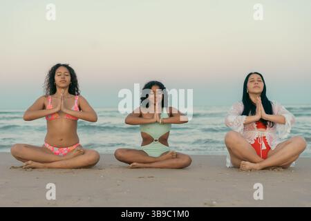 Meditating Women Practicing Yoga on the Beach Stock Photo