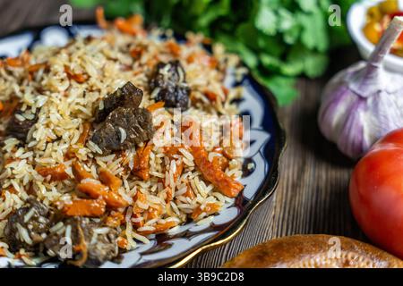 Large dish with Uzbek festive pilaf on wooden background Stock Photo