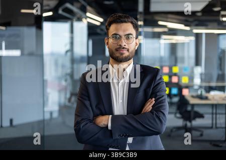 Portrait of serious confident businessman at workplace inside office. Man with crossed arms looking at camera, financier investor in business suit. Stock Photo
