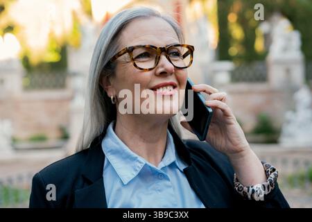 A Confident and Professional Woman Engaged in a Phone Call While Dressed in Business Attire Stock Photo