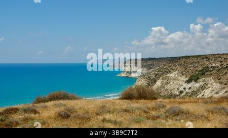 Vivid coastal landscape featuring rugged cliffs and a serene, deep blue ocean under a clear, sunny sky, showcasing the beauty of tranquil nature and p Stock Photo