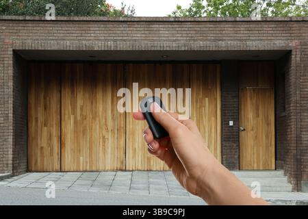 Woman using remote to control electric gate outdoors, closeup Stock Photo