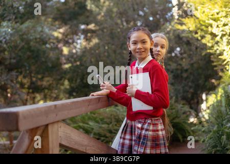 Elementary school students using tablet and smartphone in a park Stock Photo