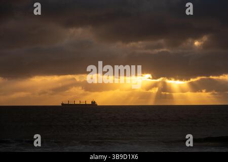 Freight Ship on the Water at Sunset with Light Rays Stock Photo
