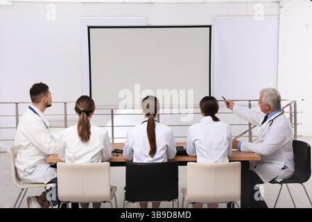 Team of doctors using video projector during conference indoors Stock Photo