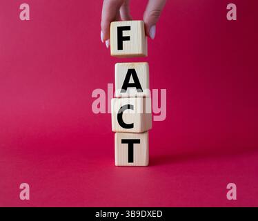 Fact symbol. Concept word Fact on wooden cubes. Businessman hand. Beautiful red background. Business and Fact concept. Copy space. Stock Photo