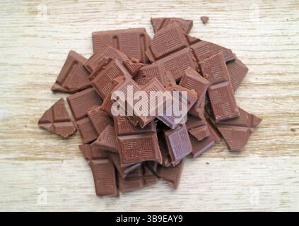 Pile of chocolate chunks isolated on wooden background Stock Photo