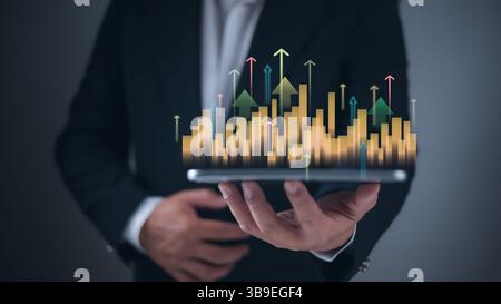 Businessman hand holding upward bar chart with glowing arrows, showing business growth, Investment analysis in digital economy, Goal success concept w Stock Photo