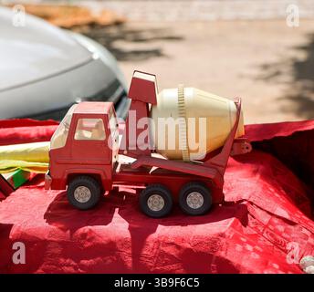 On a table is a red and yellow toy car, a concrete mixer truck Stock Photo