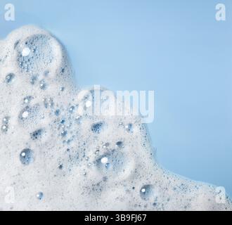 White soap foam with bubbles on a blue background, texture of the soapy or detergent foam Stock Photo