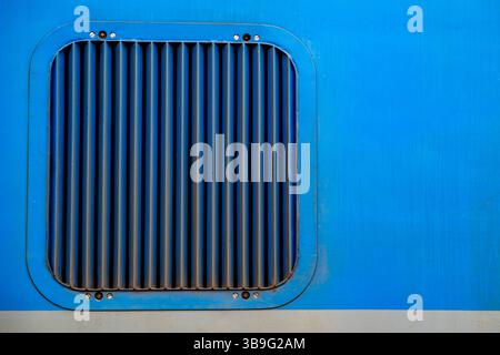 a square ventilation grille on a blue metal surface Stock Photo