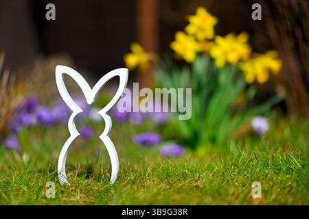 Easter bunny figure in front of spring flowers Stock Photo