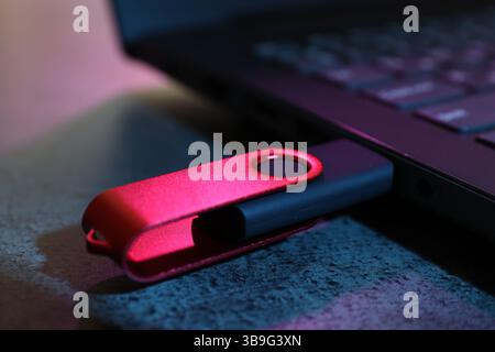 USB flash drive connected to laptop on dark grey table, closeup Stock Photo