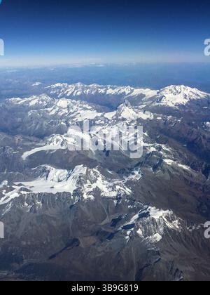 Aerial view made from plane, flying over European Alps between Italy and Austria during summer time. Top of mountains covered by snow. Stock Photo