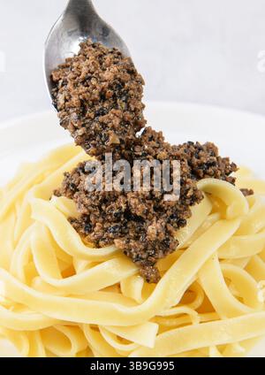 Tagliatelle pasta with chopped black truffle. Fresh Italian autumn recipe with black truffle on white plate grey table background Stock Photo