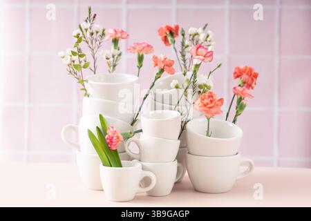Stacked white cups interspersed with vibrant spring flowers, set against a soft pastel background. The image showcases an aesthetic arrangement of tab Stock Photo