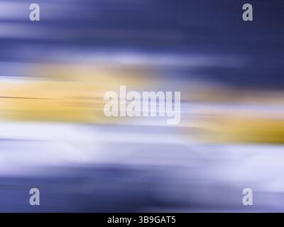 This image captures a dynamic abstract blur featuring a blend of blue and yellow with subtle transitions, ideal for vibrant, colorful backgrounds. Stock Photo
