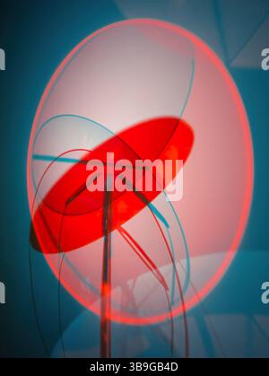 A contemporary abstract sculpture featuring overlapping geometric forms in shades of red and blue, set against a grey background Stock Photo