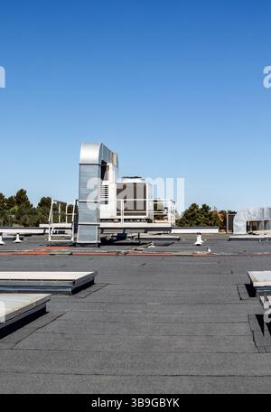 Industrial rooftop air conditioning units under a clear blue sky on a sunny day. The setup highlights the importance of efficient climate control in c Stock Photo