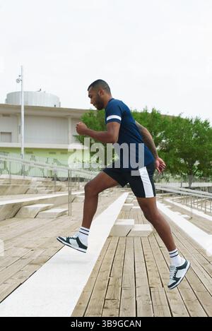 Athletic black man running up outdoor stairs, demonstrating strength and endurance. The dynamic scene captures fitness, determination, and an active l Stock Photo