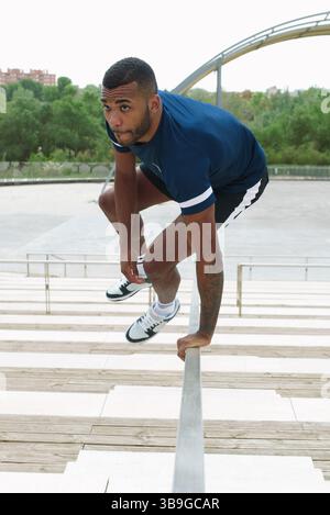 A black male athlete energetically practicing parkour on an outdoor staircase, showcasing agility and determination in an urban environment. Perfect f Stock Photo