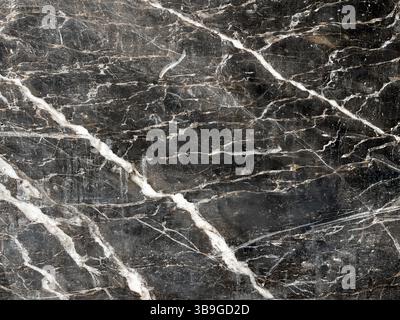 Detailed close-up of a dark marble surface with intricate white veining, showcasing natural elegance and rich texture, perfect for architectural or de Stock Photo