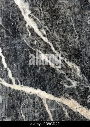High-resolution close-up image of a black marble surface showcasing intricate veining and natural patterns. Ideal for backgrounds, textures, and desig Stock Photo
