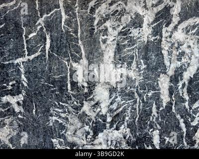 Close-up image of a textured stone surface showcasing intricate natural patterns and colors. The blend of gray and white creates an abstract, artistic Stock Photo