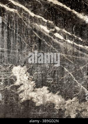 A detailed dark marble texture featuring striking natural white veins running across its surface. This elegant pattern is ideal for backgrounds or des Stock Photo