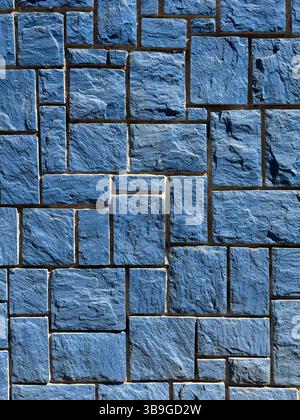 A detailed image of a blue stone wall featuring interlocking rectangular tiles with a rough texture. The stones are arranged in a geometric pattern pr Stock Photo