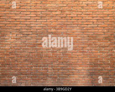 A detailed image of a red brick wall showcasing uniform brickwork and mortar lines. The texture and color variations create an industrial and rustic a Stock Photo