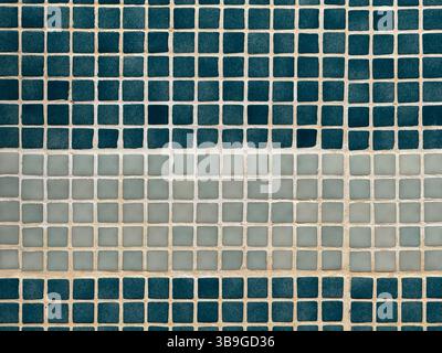 A close-up view of a wall featuring a pattern of square tiles. The arrangement includes alternating rows of dark blue and light beige squares, creatin Stock Photo