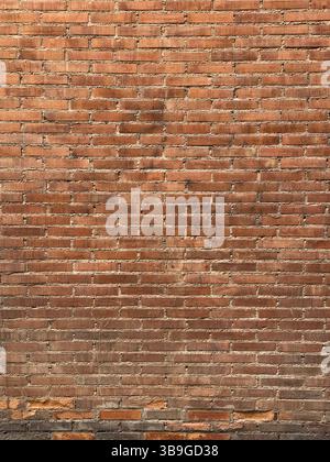 A textured red brick wall with a consistent horizontal pattern. The bricks are evenly laid, providing a rustic and classic look suitable for backgroun Stock Photo