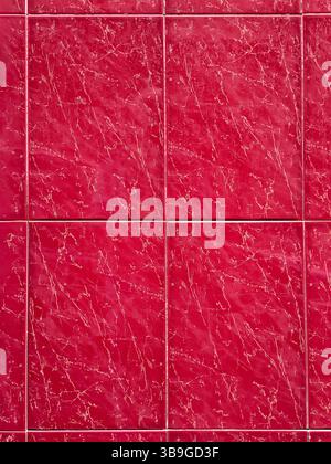 Close-up view of deep red marble tiles featuring a natural veining pattern. The vibrant color and distinct lines create a luxurious and elegant aesthe Stock Photo
