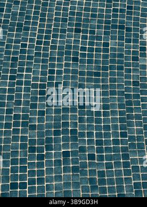 This image showcases an irregular blue mosaic pattern made of small square tiles. The textured design creates a wavy effect, adding depth and visual i Stock Photo