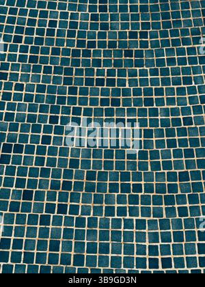 A visually captivating abstract image of a blue tiled wall, featuring a geometric mosaic pattern. The repetitive squares create an engaging texture an Stock Photo