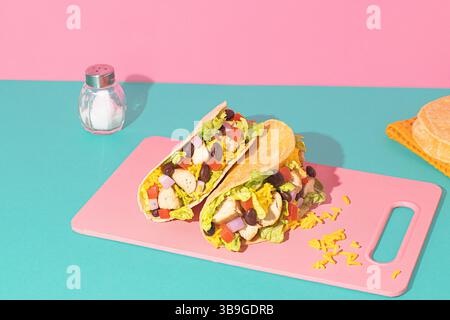 From above delicious Mexican tacos filled with grilled chicken, yellow rice, black beans, crisp lettuce, fresh tomatoes, and diced onions, presented o Stock Photo