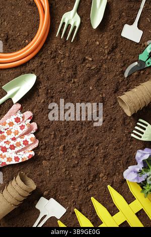 Top down view of garden tools, gloves, and seedlings arranged around rich soil. Perfect for illustrating a gardening theme with tools and earthy textu Stock Photo