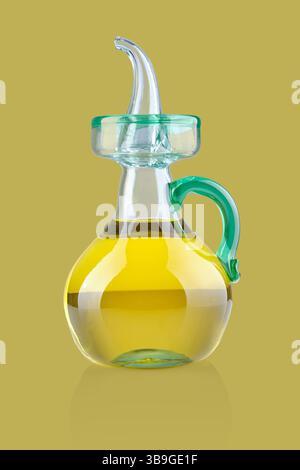 Studio shot of olive oil in a glass bottle with a green handle and spout, reflecting on a surface Stock Photo
