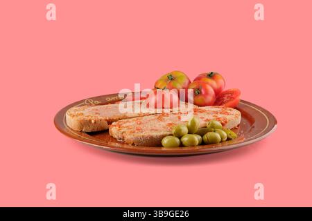 Typical catalan breakfast, pa amb tomaquet with sobrassada, served with olives and tomatoes on a brown plate Stock Photo