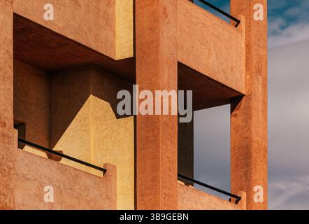 Modern architectural facade featuring geometric patterns and warm, textured surfaces. The play of light and shadow adds depth and highlights the build Stock Photo