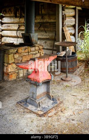 Red anvil on display in front of the blacksmith forge as a vintage display at a roadside market in rural Alabama, USA. Stock Photo