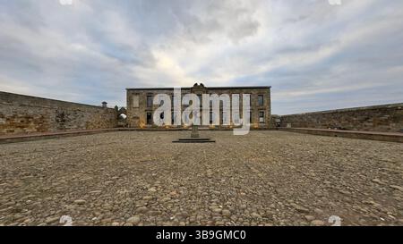 Building facade, cobblestone courtyard with statue. Stone walls on either side. Overcast sky. Symmetrical composition in Whitby Stock Photo