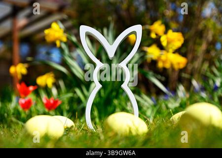 Easter bunny figure with Easter eggs in front of spring flowers Stock Photo