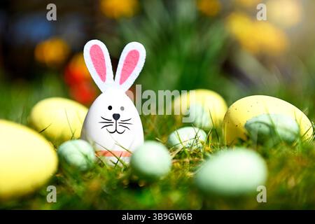Funny Easter egg with bunny ears and Easter eggs in front of spring flowers Stock Photo