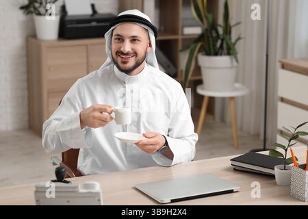 Arab businessman with cup of coffee at table in office Stock Photo