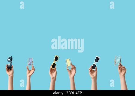 Female hands holding mini deck chairs with sunglasses on blue background Stock Photo