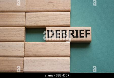 Debrief symbol. Concept word Debrief on wooden blocks. Beautiful grey green background. Business and Debrief concept. Copy space. Stock Photo